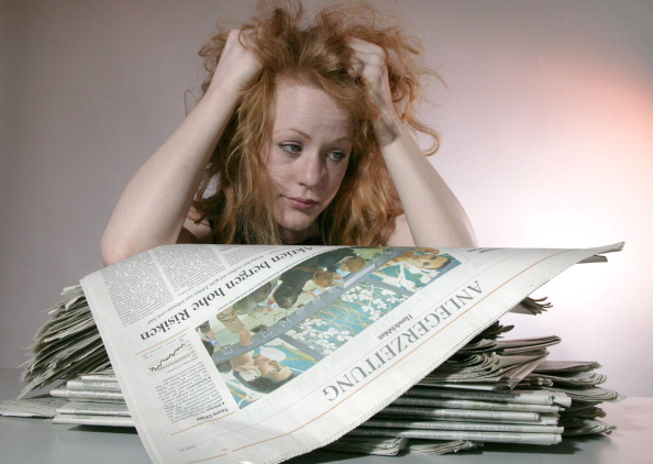 Woman pulling out her hair while looking at financial newspapers, Symbol: many people are not sufficiently informed about the options of investments.