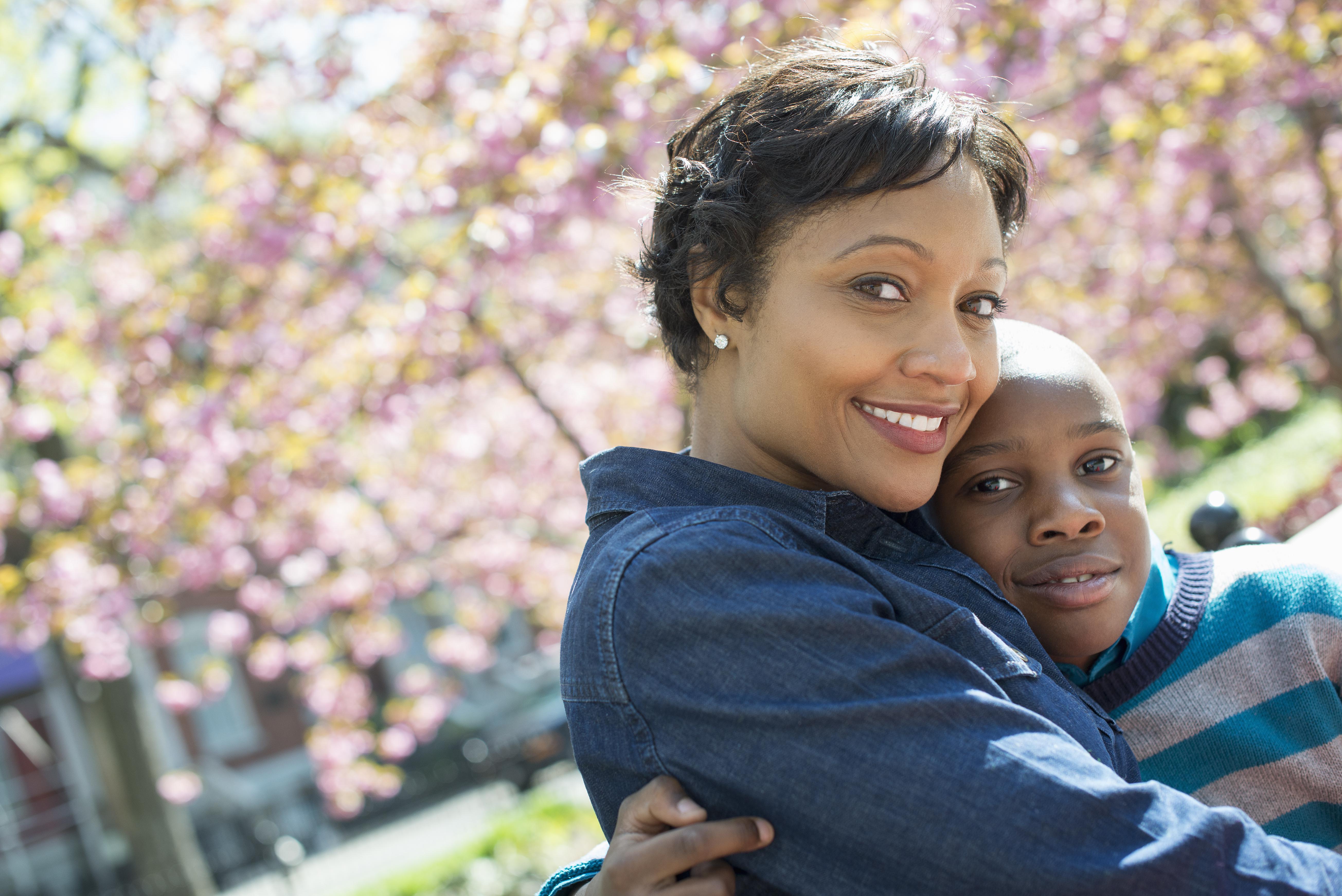 A New York city park in the spring. Sunshine and cherry blossom. A mother and son spending time together.