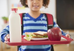 African American school girl holding lunch on a tray