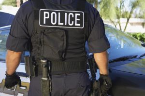 Police officer in bulletproof vest outdoors, back view