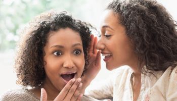 Surprised women whispering secrets