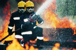 Firefighters Holding a Hose and Spraying Water