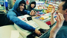 High Angle View of Two Robbers Robbing a Cash Till and Threatening a Shop Assistant with a Gun