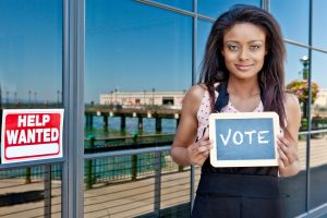 Young woman holding a sign that says 'VOTE'