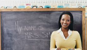 Portrait of a Teacher Standing Next to a Blackboard in a Classroom