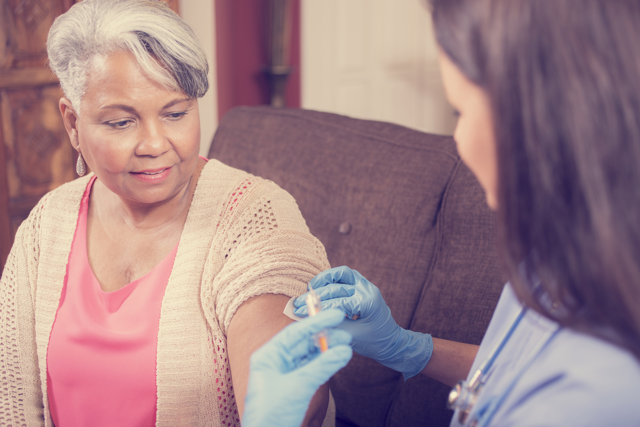 Home healthcare nurse giving injection to senior adult woman.