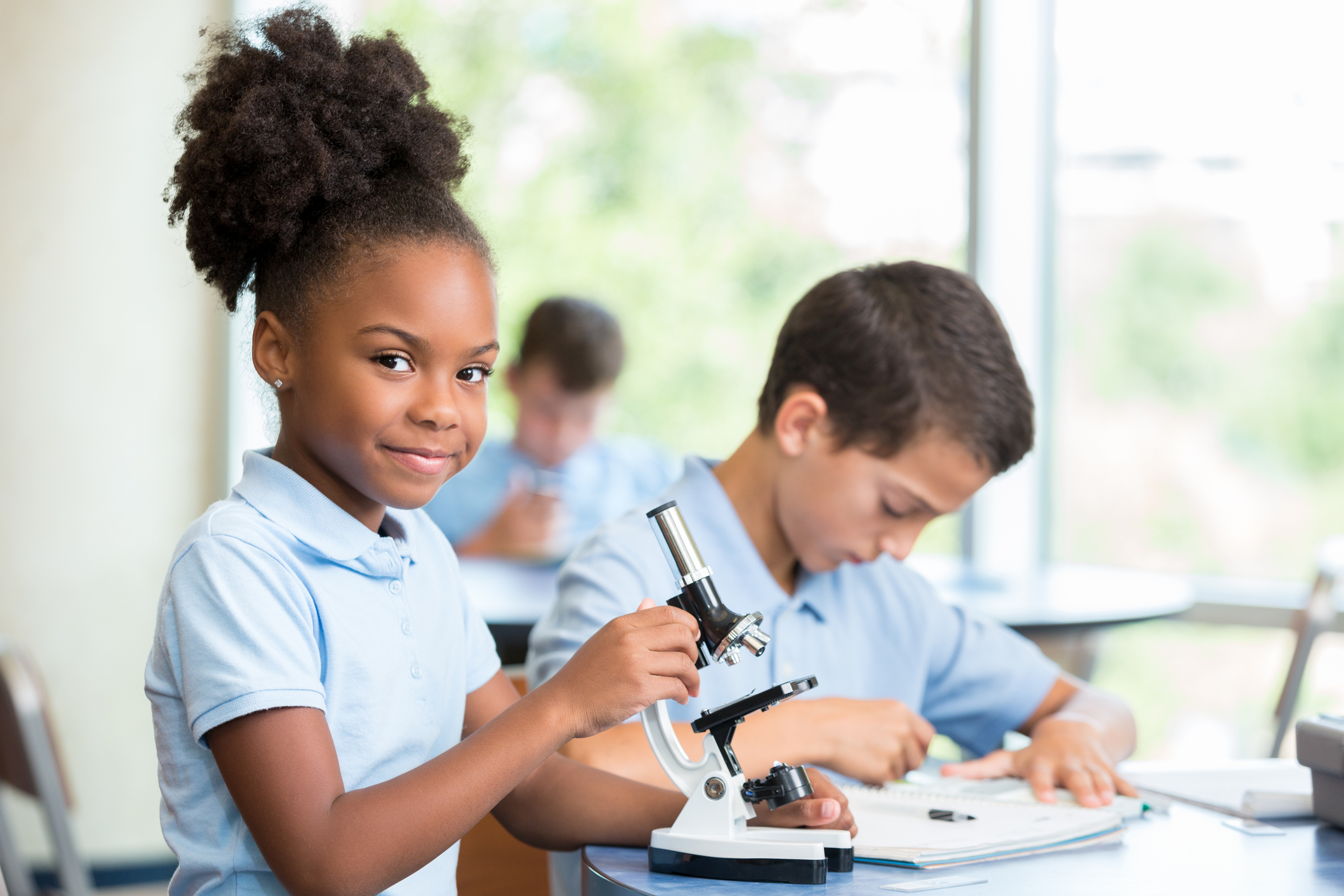 Cheerful African American elementary schoolgirl works on science project