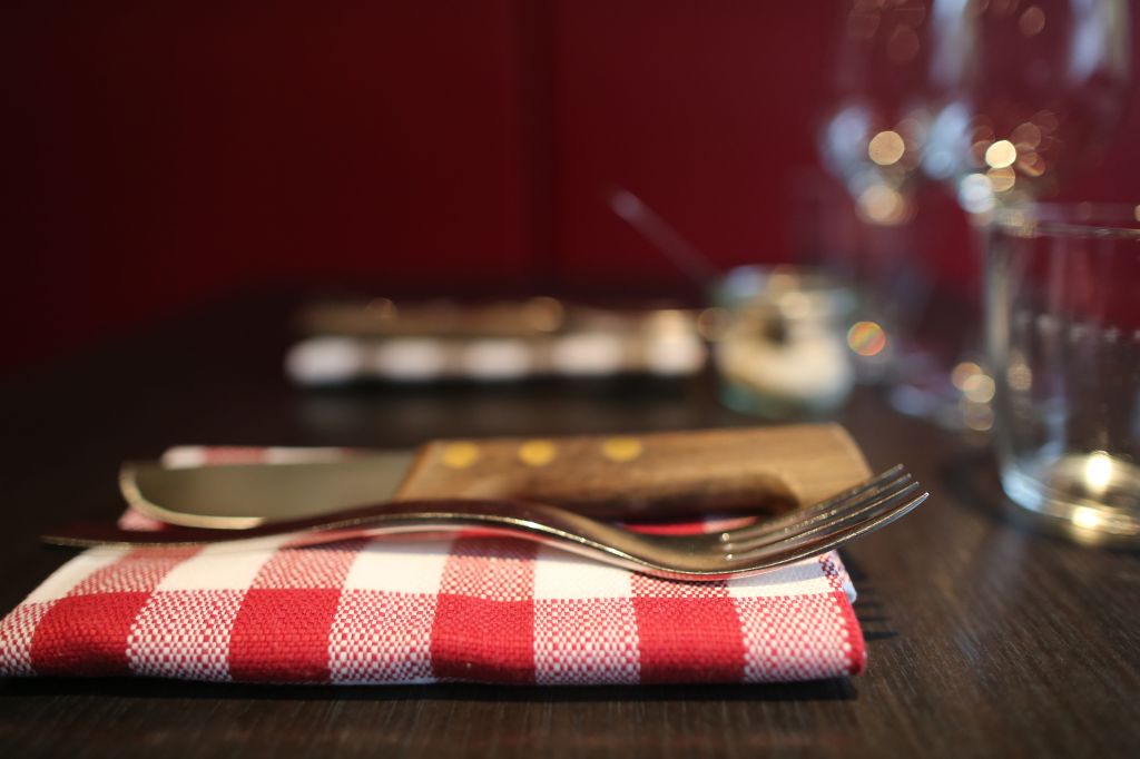 Place setting on dining table. Fork, knife and glass.