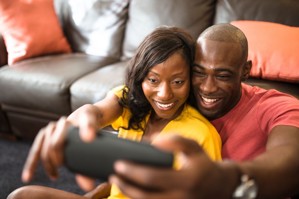 afro couple take a selfie on the couch