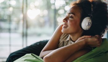 Happy black woman enjoying in sound of good music over headphones.