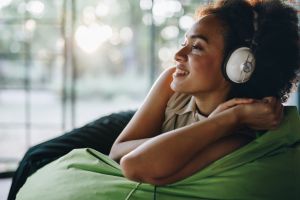Happy black woman enjoying in sound of good music over headphones.
