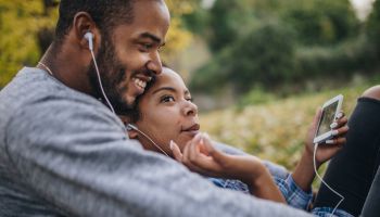 African American couple enjoying in MP3 music at the park.