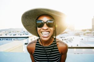 Black woman wearing sun hat and sunglasses on rooftop