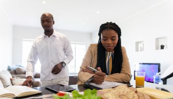 Businessman and woman preparing to make lunch while they do some work.