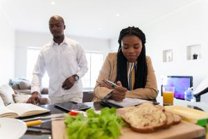 Businessman and woman preparing to make lunch while they do some work.