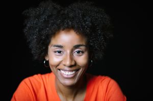 Smiling Woman With Curly Hair On Black Background