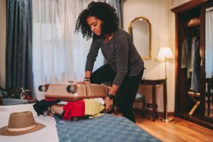 Mixed race woman struggling with overflowing suitcase before journey