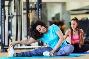 Women sitting on ground and stretching in gym