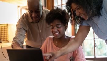 Parents helping daughter while using computer