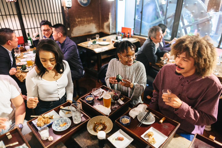 Group of mixed-raced travelers enjoying drinking alcohol in Japanese style pub