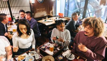 Group of mixed-raced travelers enjoying drinking alcohol in Japanese style pub