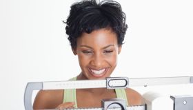 Close up of an African American Woman on a scale and looking happy.