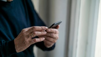 Close-up of senior man using cell phone at home