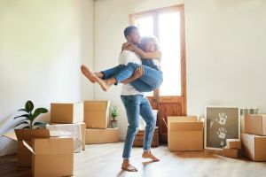 Happy young man carrying woman into new house