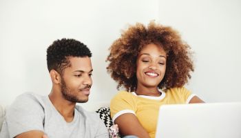 Smiling couple watching movie on laptop at home