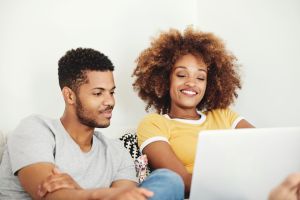 Smiling couple watching movie on laptop at home
