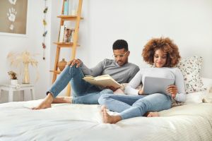 Couple reading book and using digital tablet