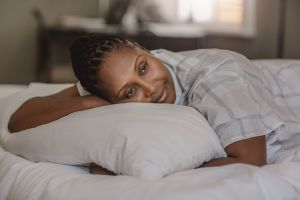 Smiling African American woman lying in bed lost in thought
