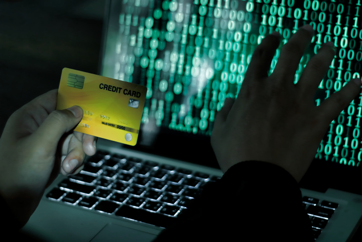 Credit Cards Theft Concept. Hacker with Credit Cards on His Laptop Using Them For Unauthorized Shopping