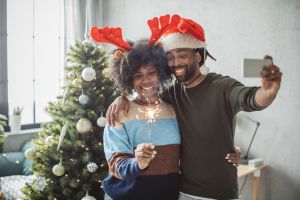 Couple decorating Christmas tree and take photos