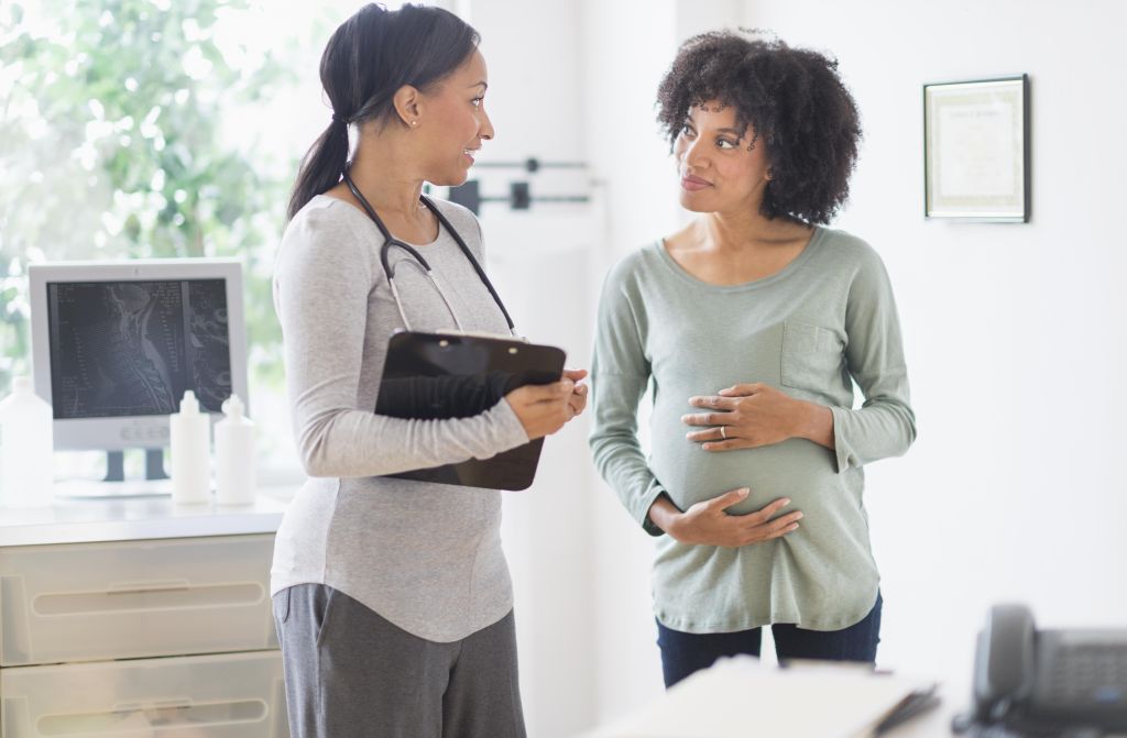 African American doctor talking to pregnant woman