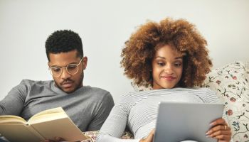Young couple reading book and using digital tablet