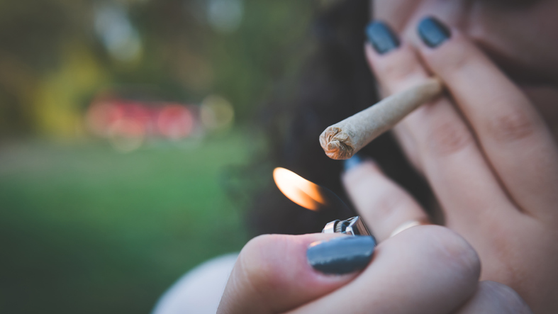 Cropped Image Of Woman Lighting Marijuana Joint