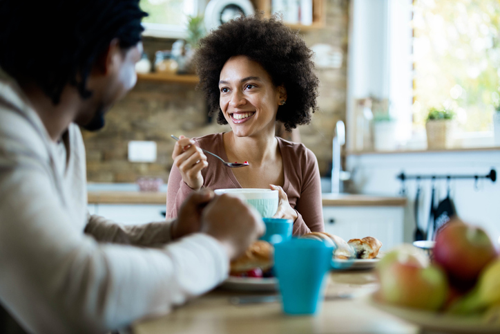 Happy black woman talking to her boyfriend during breakfast at home.
