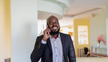 Self-Confident African Businessman at Home Using a Mobile Phone