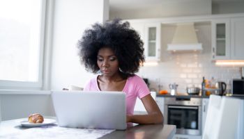 African woman sitting at home, using laptop