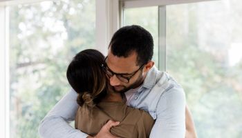 Mid adult husband gives unrecognizable military wife hug