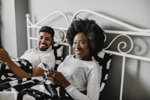 Couple using smart phone in bed