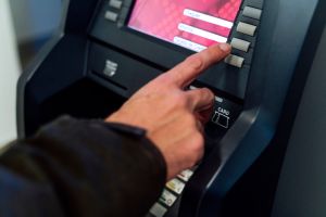 Man typing secret number from a bank ATM to withdraw money
