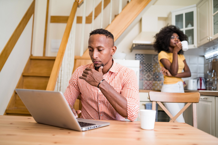 Young couple in the kitchen room drinking coffee and using laptop at home
