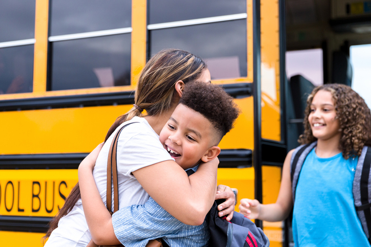 Unrecognizable mid adult mom gives children hugs before school