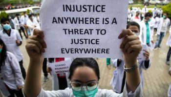 A doctor wearing a facemask holds out a protest placard...