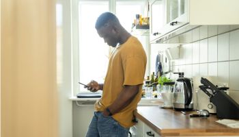 Man using smart phone in kitchen at home
