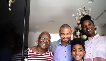Portrait of a happy family opening the house door, christmas tree in the background