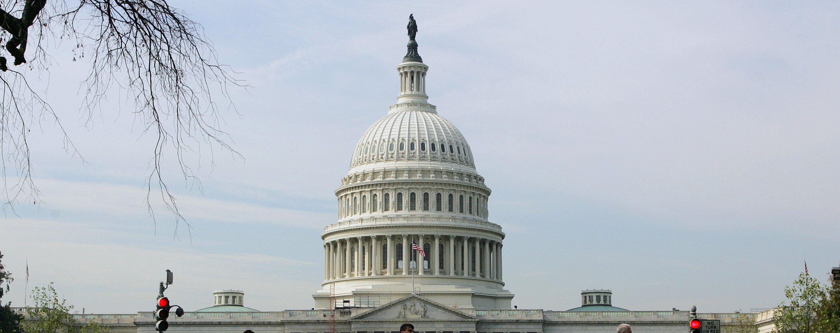 Pedestrians walk past the US Capitol and