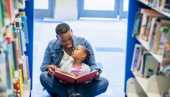 Mother reading to little girl at the library